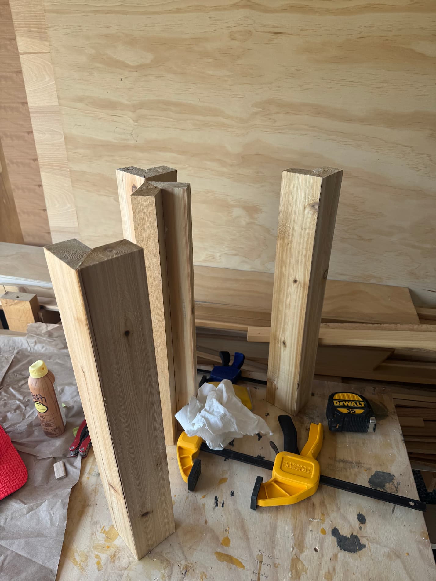 Picture of L shaped four blocks of wood standing on a workbench. Each L shaped block has been made with two pieces of wood cut at a 45 degree angle and glued together. 